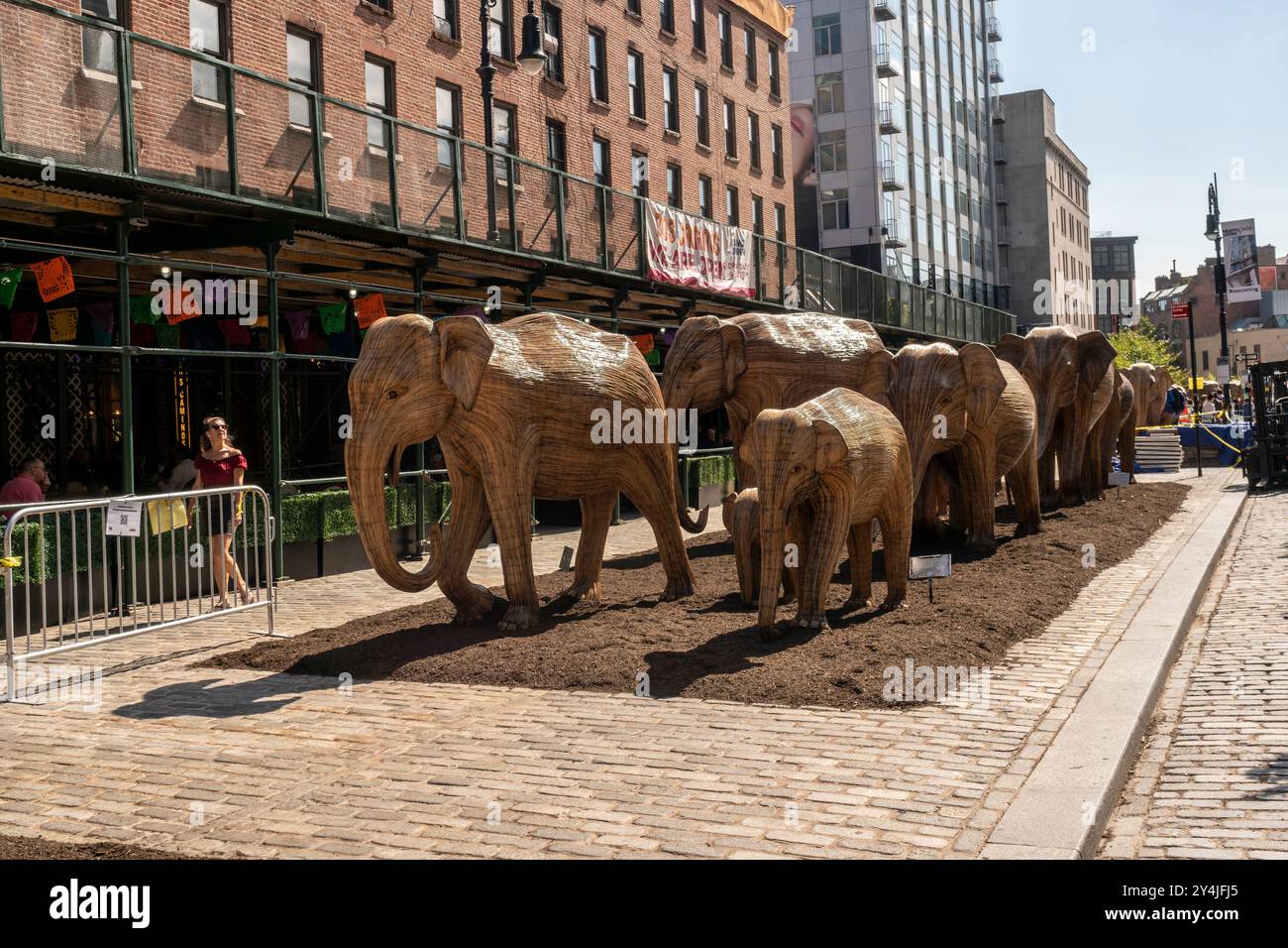 Le persone sono incantate dall'installazione d'arte pubblica Great Elephant Migration nel Meatpacking District di New York giovedì 5 settembre 2024. Le 100 statue sono state create dal collettivo di coesistenza la cui missione aiuta le persone a condividere lo spazio con la natura magnifiche creature. Gli elefanti furono costruiti da artigiani indigeni indiani della Lantana camara, una specie di piante invasiva. L'installazione sarà visibile fino al 20 ottobre. (© Richard B. Levine) Foto Stock