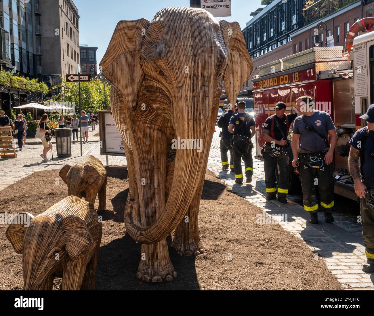 I membri della FDNY vedono l'installazione d'arte pubblica Great Elephant Migration nel Meatpacking District di New York martedì 10 settembre 2024. Le 100 statue sono state create dal collettivo di coesistenza la cui missione aiuta le persone a condividere lo spazio con la natura magnifiche creature. Gli elefanti furono costruiti da artigiani indigeni indiani della Lantana camara, una specie di piante invasiva. L'installazione sarà visibile fino al 20 ottobre. (©ÊRichard B. Levine) Foto Stock