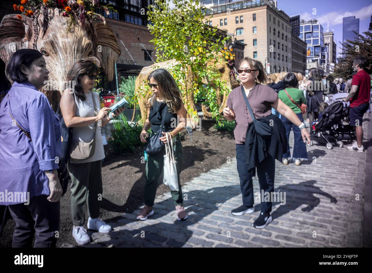 Le persone sono incantate dall'installazione d'arte pubblica Great Elephant Migration nel Meatpacking District di New York domenica 8 settembre 2024. Le 100 statue sono state create dal collettivo di coesistenza la cui missione aiuta le persone a condividere lo spazio con la natura magnifiche creature. Gli elefanti furono costruiti da artigiani indigeni indiani della Lantana camara, una specie di piante invasiva. L'installazione sarà visibile fino al 20 ottobre. (© Richard B. Levine) Foto Stock