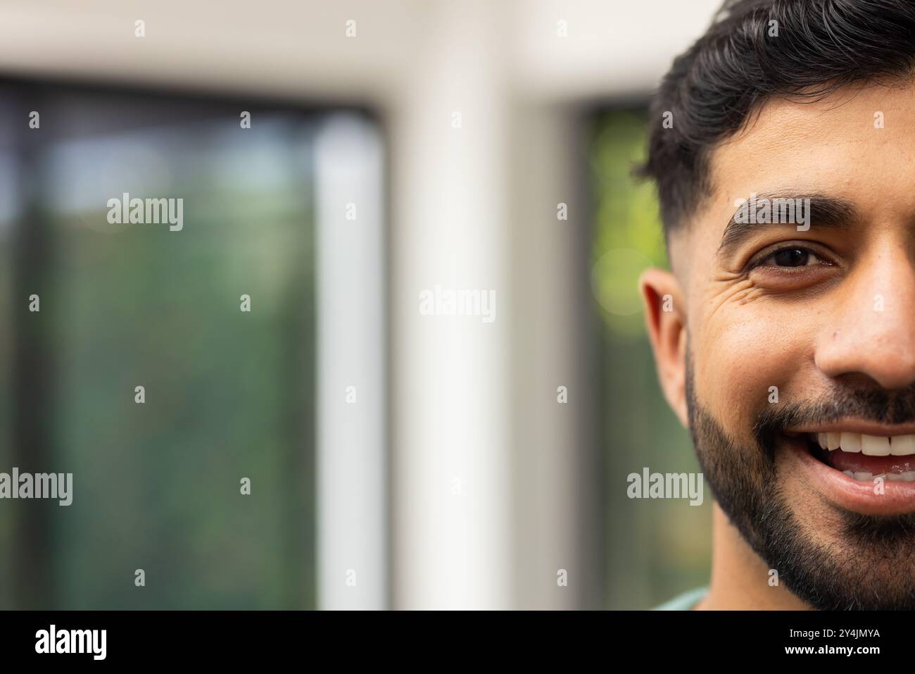 Giovane indiano sorridente con la barba che si gode il tempo in casa, ritratti ravvicinati, spazio fotocopie Foto Stock