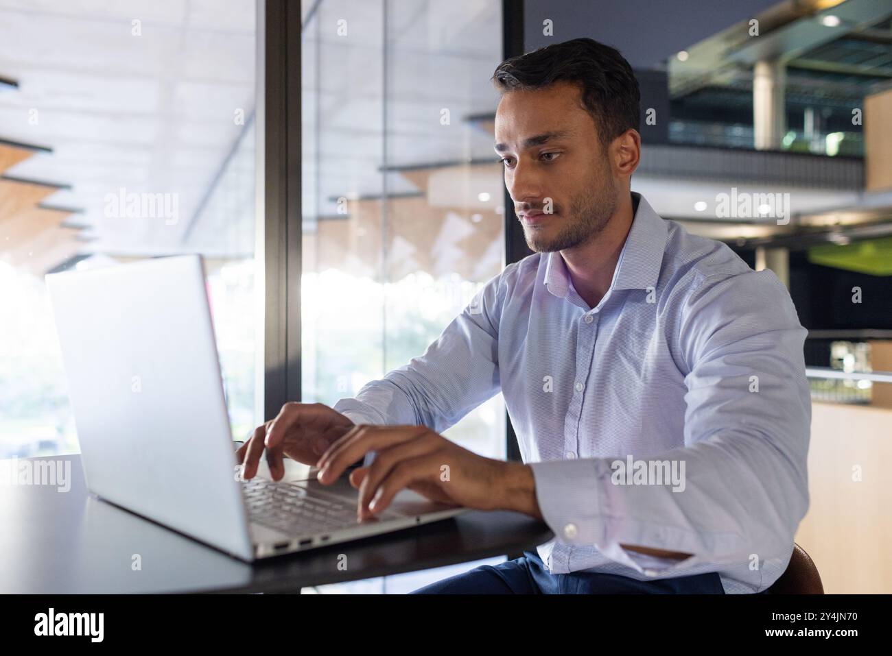 Lavorando su un laptop, uomo d'affari che si occupa di attività in un ambiente d'ufficio moderno Foto Stock