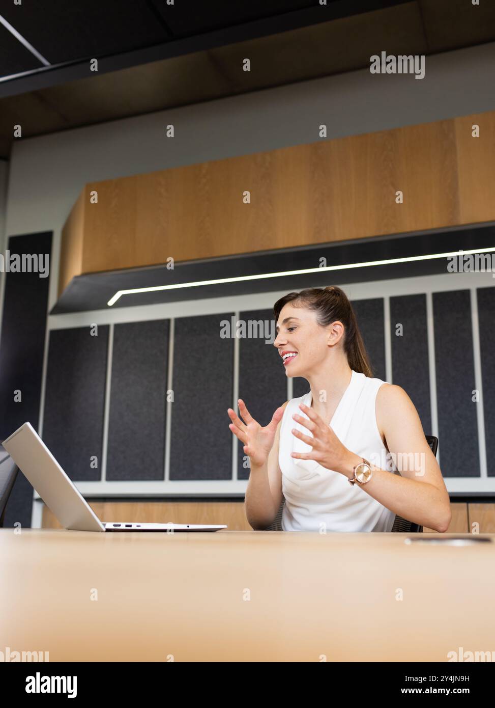 Donna d'affari sorridente che utilizza un computer portatile per videoconferenze in un ufficio moderno, spazio fotocopie Foto Stock