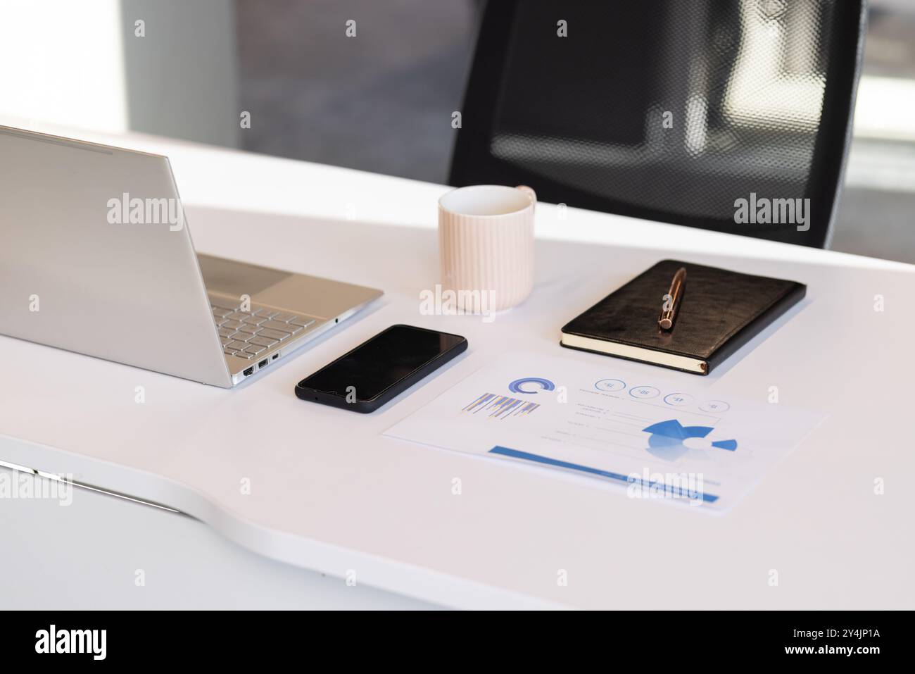 Laptop, smartphone, notebook e tazza di caffè su una moderna scrivania da ufficio Foto Stock