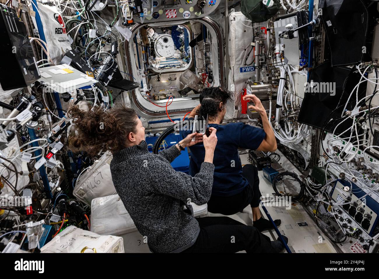 Stazione spaziale Internazionale, orbita terrestre. 15 settembre 2024. L'astronauta della NASA Tracy Caldwell-Dyson, a sinistra, taglia i capelli dell'astronauta Suni Williams all'interno del modulo di laboratorio Columbus a bordo della stazione spaziale Internazionale, 15 settembre 2024, in Earth Orbit. Credito: Astronaut provided/NASA Photo/Alamy Live News Foto Stock