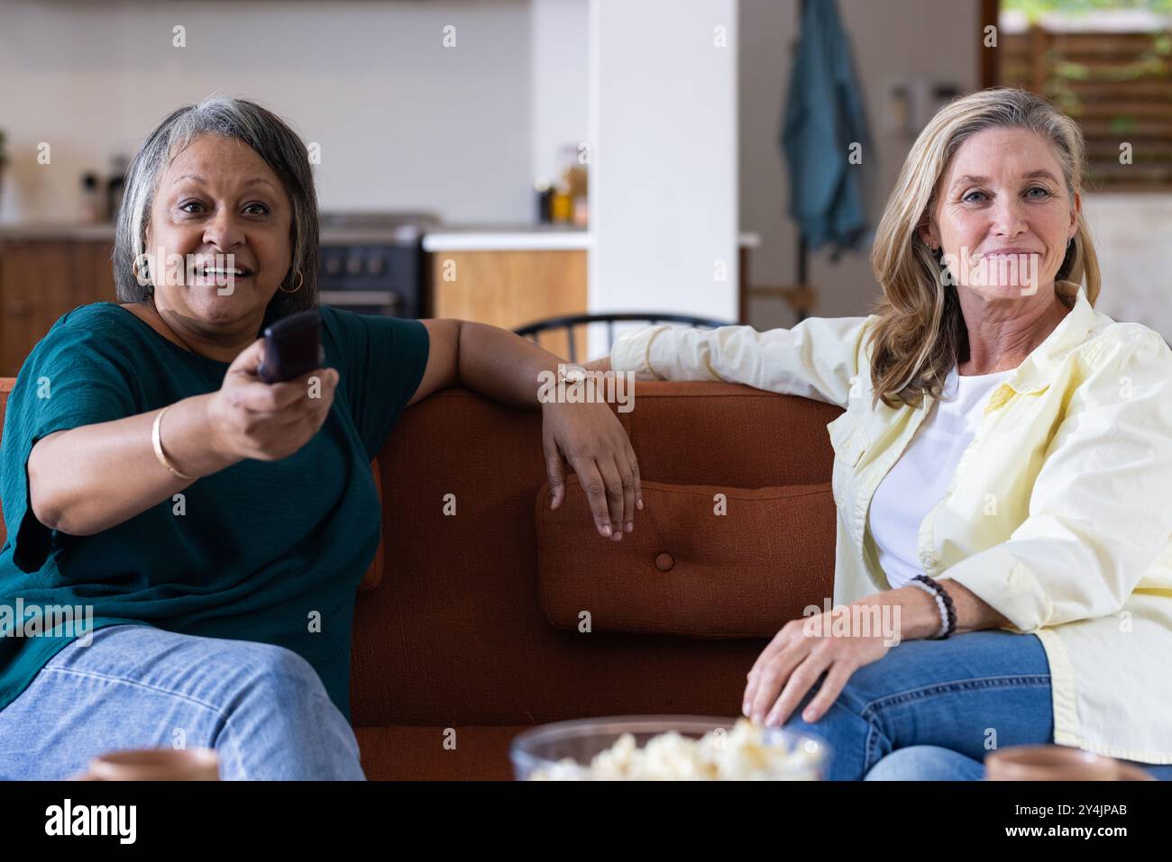 A casa, guardando la TV, due donne anziane si rilassano sul divano e si divertono insieme Foto Stock