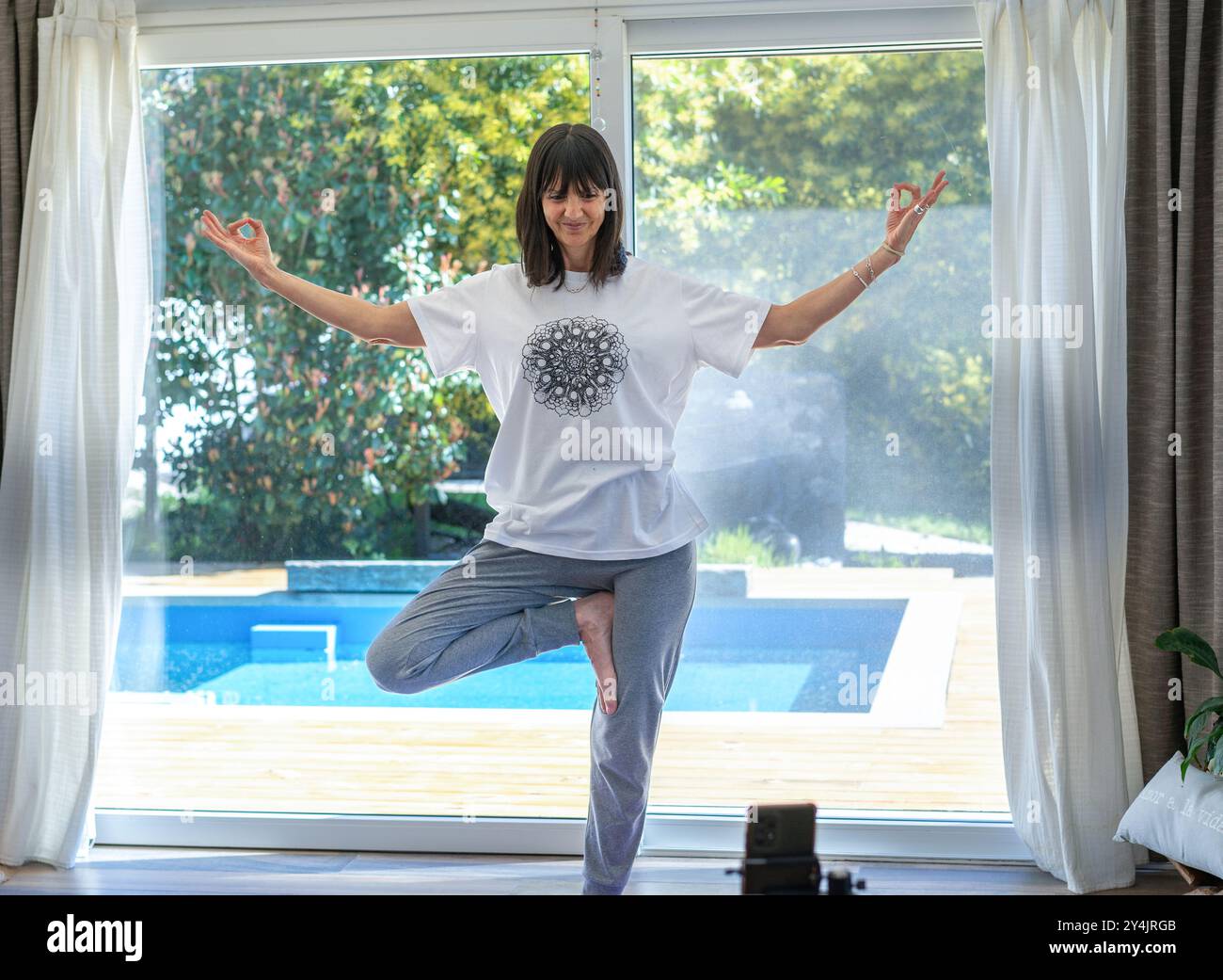 Istruttore di yoga a casa che filma contenuti coinvolgenti per i suoi seguaci sui social media Foto Stock