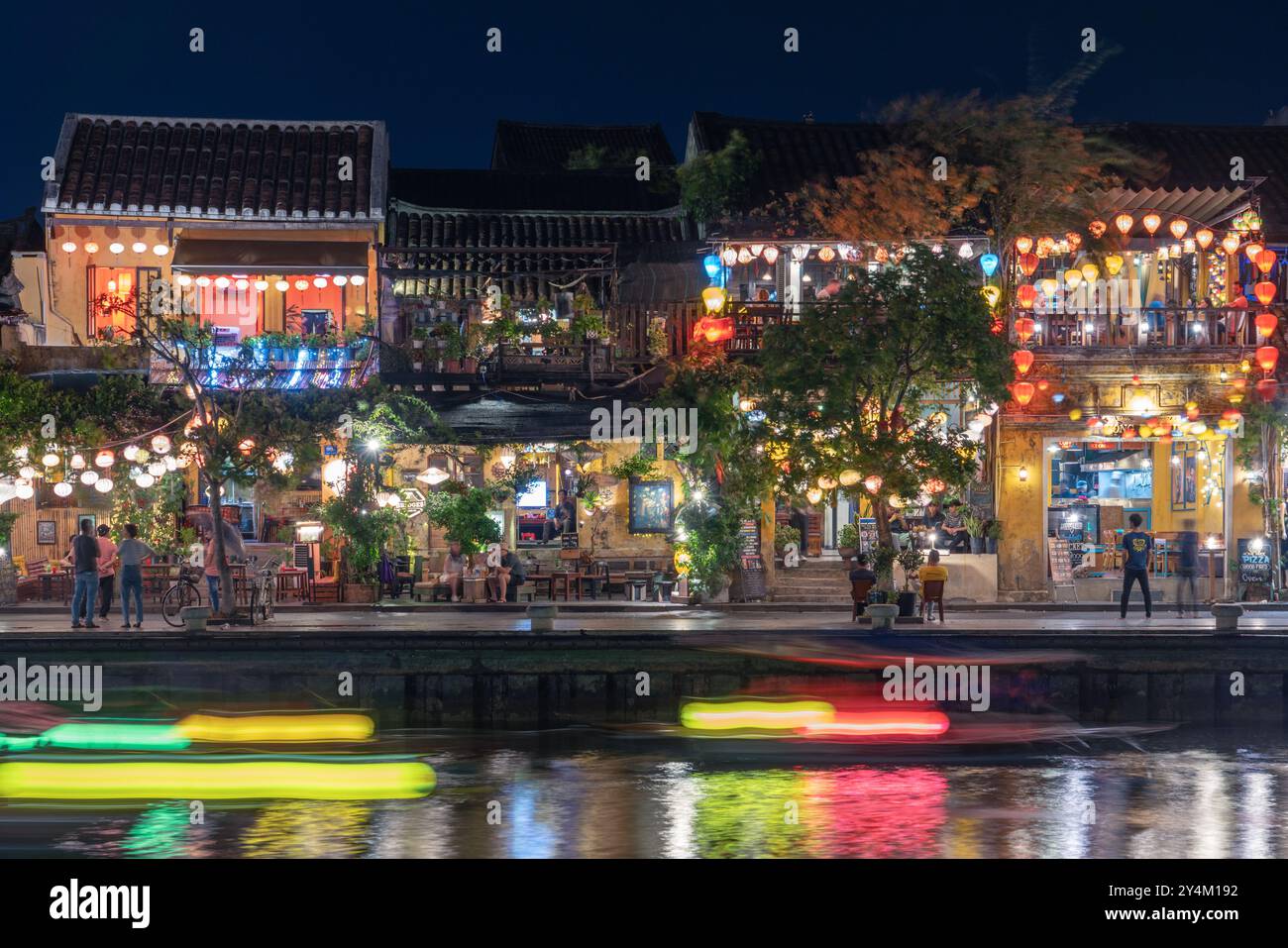 Colorati edifici storici con tradizionali lanterne vietnamite lungo il fiume di notte il 24 maggio 2023, a Hoi An, Vietnam Foto Stock