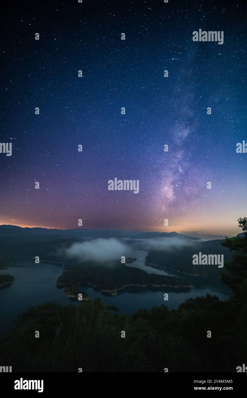 Un cielo notturno mozzafiato illumina un tranquillo lago a Crocodile Island. La via Lattea si estende attraverso l'orizzonte, gettando il suo bagliore etereo su t Foto Stock