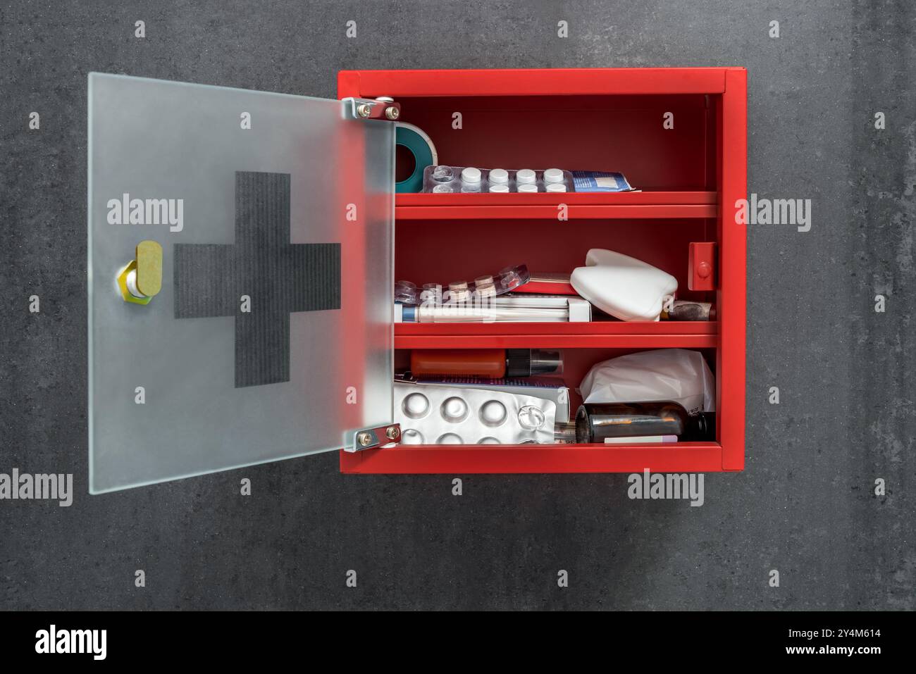Armadio medico in metallo rosso aperto pieno di farmaci appesi su Uno sfondo grigio scuro della parete in marmo. Vista frontale Foto Stock