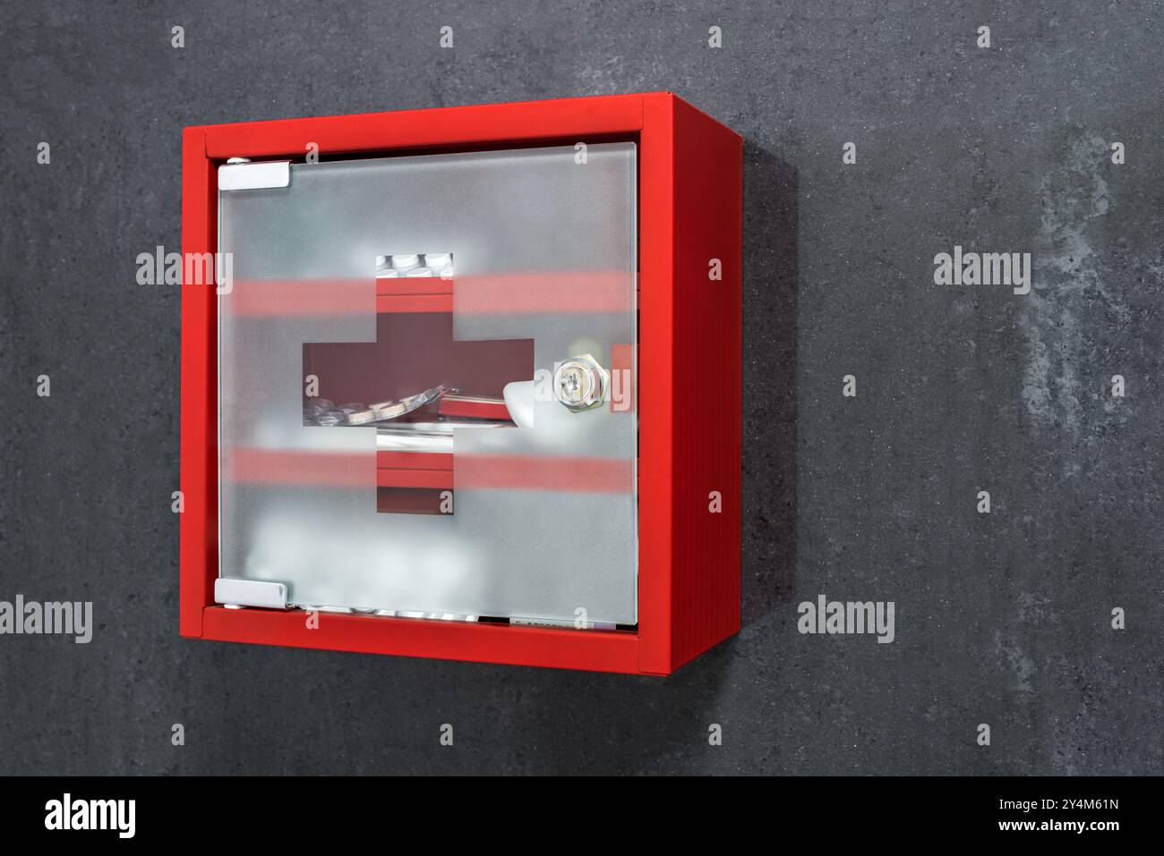 Armadio medico metallico rosso chiuso pieno di farmaci appesi su Una parete di marmo grigio scuro. Vista in prospettiva Foto Stock