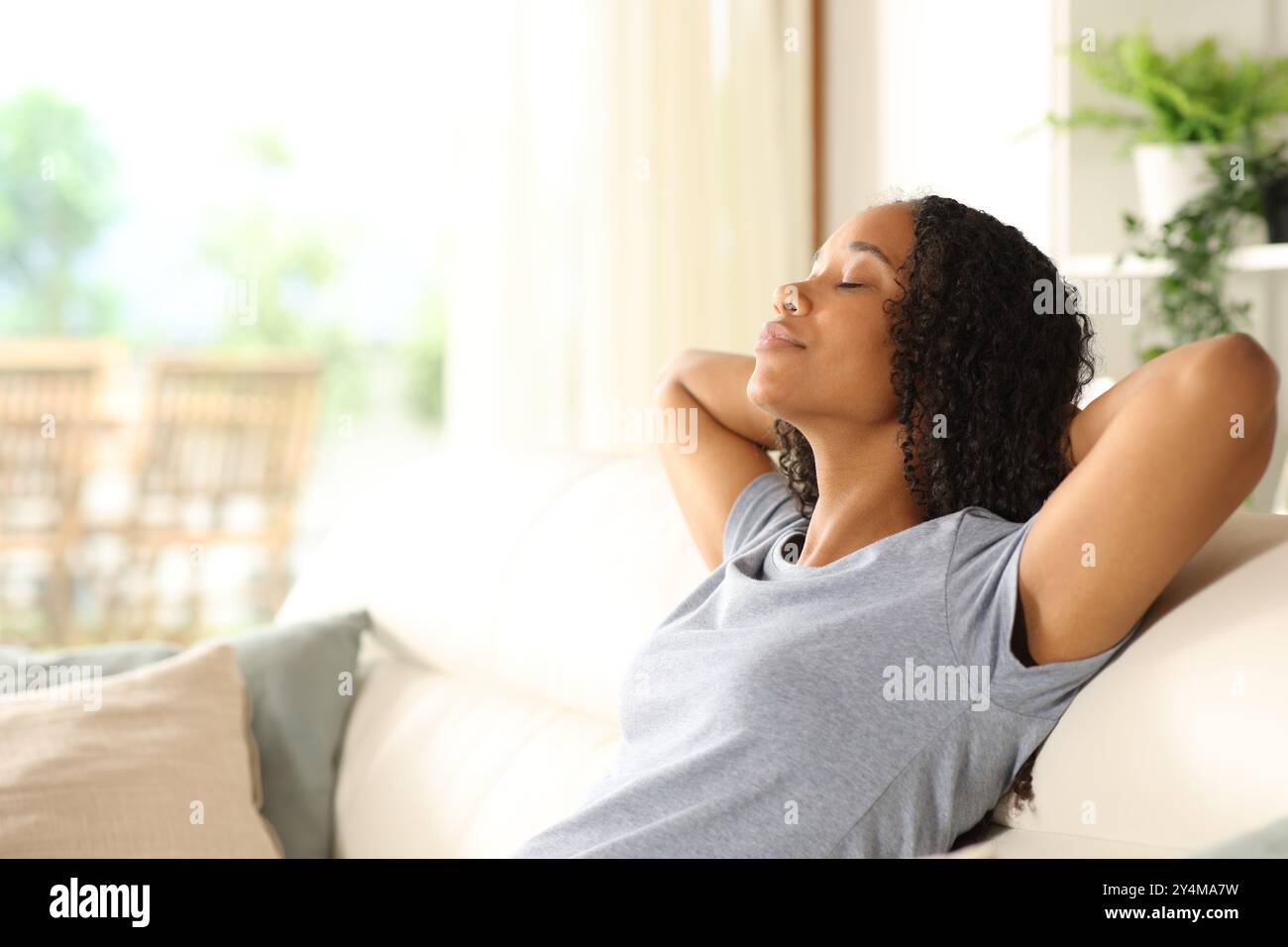 Donna nera informale che si rilassa seduto su un divano a casa Foto Stock