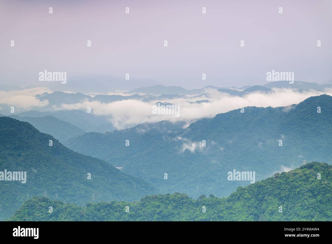 Una tranquilla catena montuosa è avvolta da una coperta di nebbia, creando un'atmosfera da sogno ed eterea. Gli strati di colline e valli si estendono nella Foto Stock