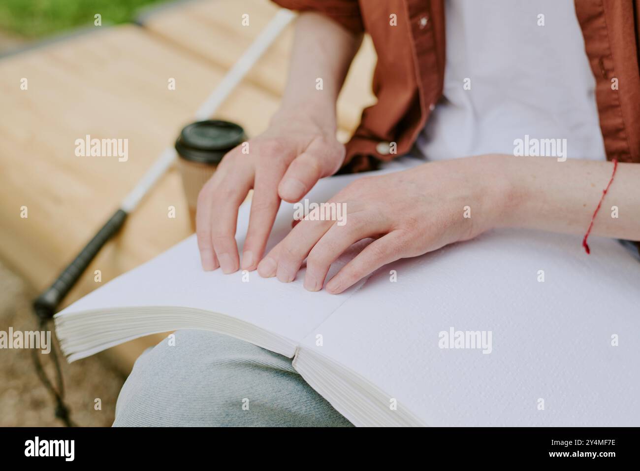 Ripresa ad angolo alto di mani maschili irriconoscibili toccando la pagina in rilievo del libro in parco Foto Stock