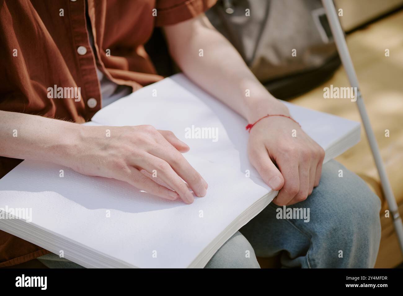 Primo piano medio di mani maschili irriconoscibili che toccano la pagina con il sistema di scrittura Braille Foto Stock