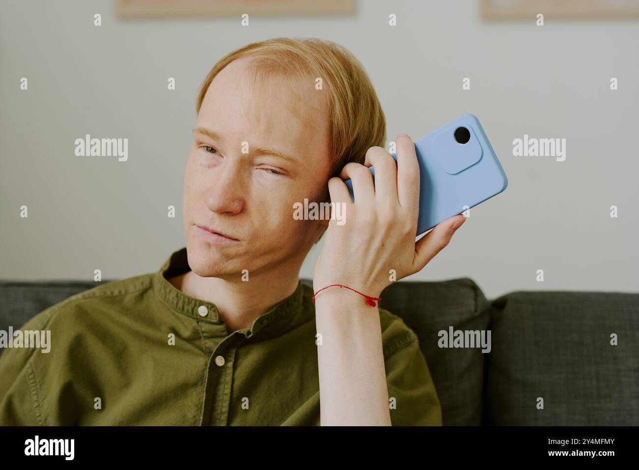 Primo piano medio di un uomo con disabilità che utilizza il suo smartphone per ascoltare i messaggi vocali degli amici Foto Stock
