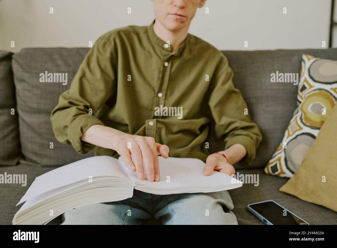 Primo piano medio del libro Braille sulle ginocchia di un uomo irriconoscibile con disabilità Foto Stock