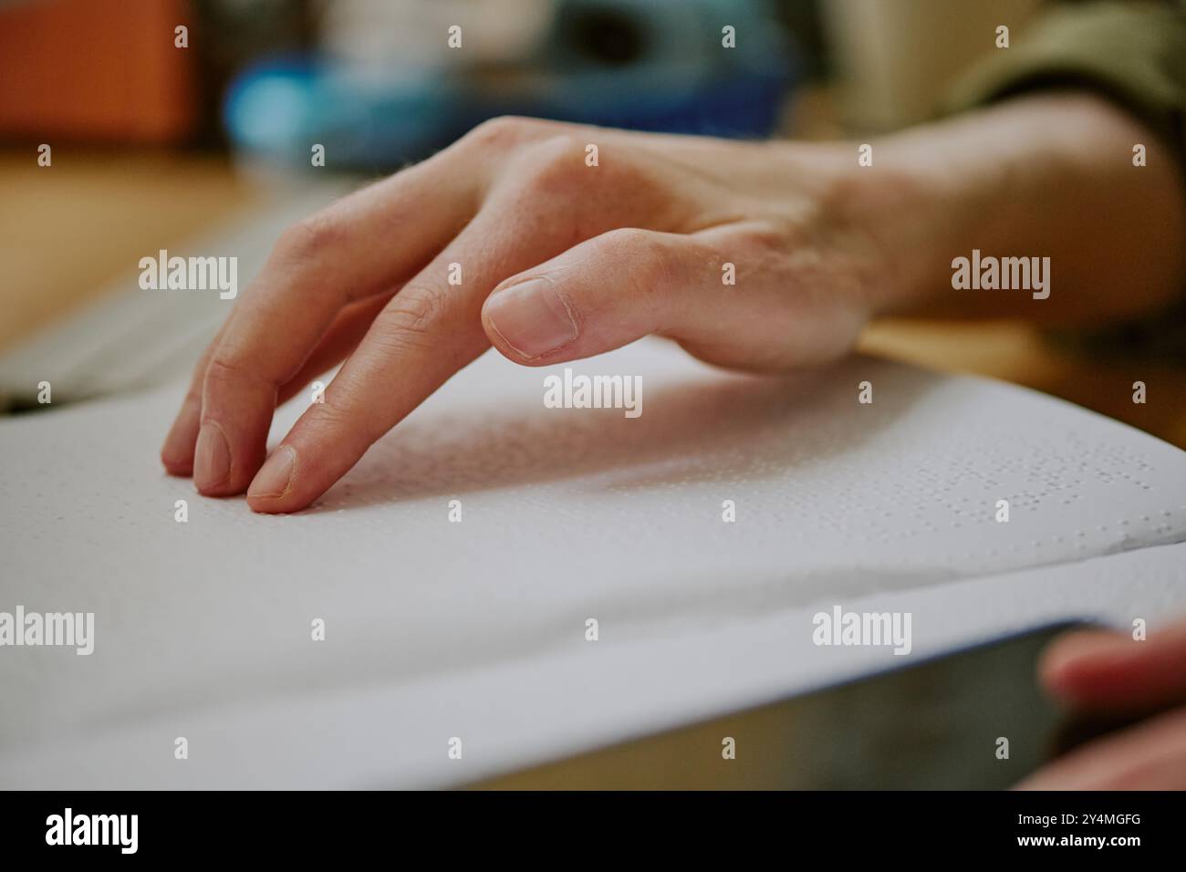 Primo piano medio di una mano maschile irriconoscibile che tocca la carta in rilievo del libro Braille Foto Stock