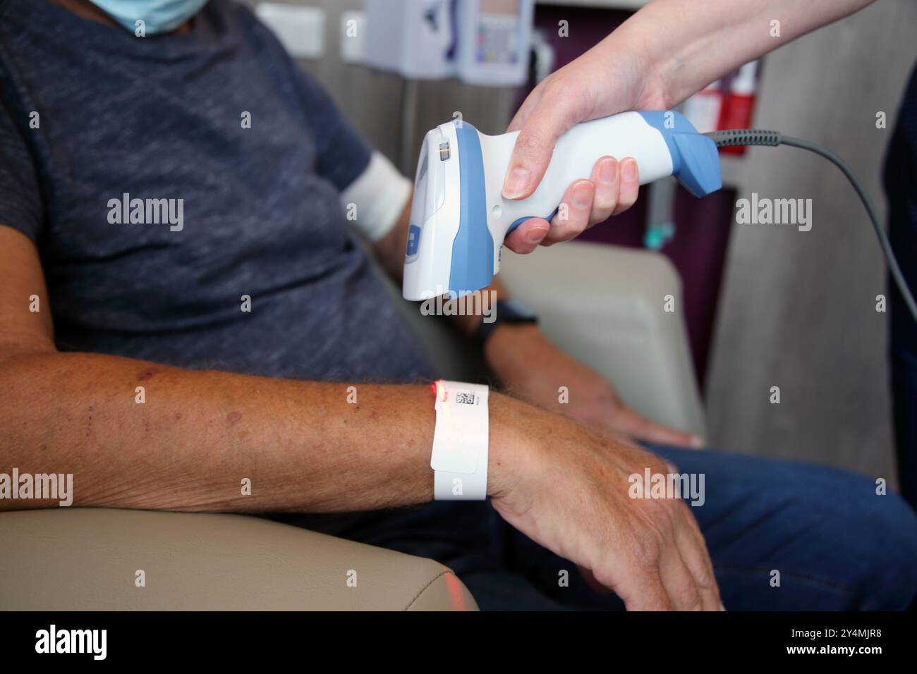 Infermiere che scansiona il codice QR sul braccialetto ID cartaceo dei pazienti in ospedale Surrey Inghilterra Foto Stock