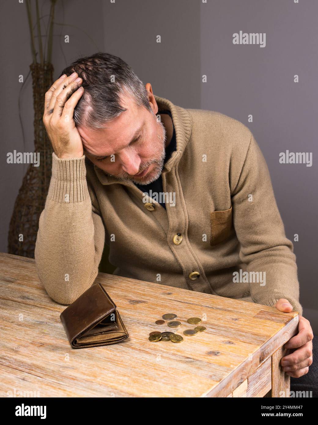 Uomo che guarda un portafoglio vuoto con monete piccole. Povero uomo senza soldi nel portafoglio. Difficoltà finanziarie. Basso reddito per le persone di mezza età. Perdita di lavoro. Po Foto Stock