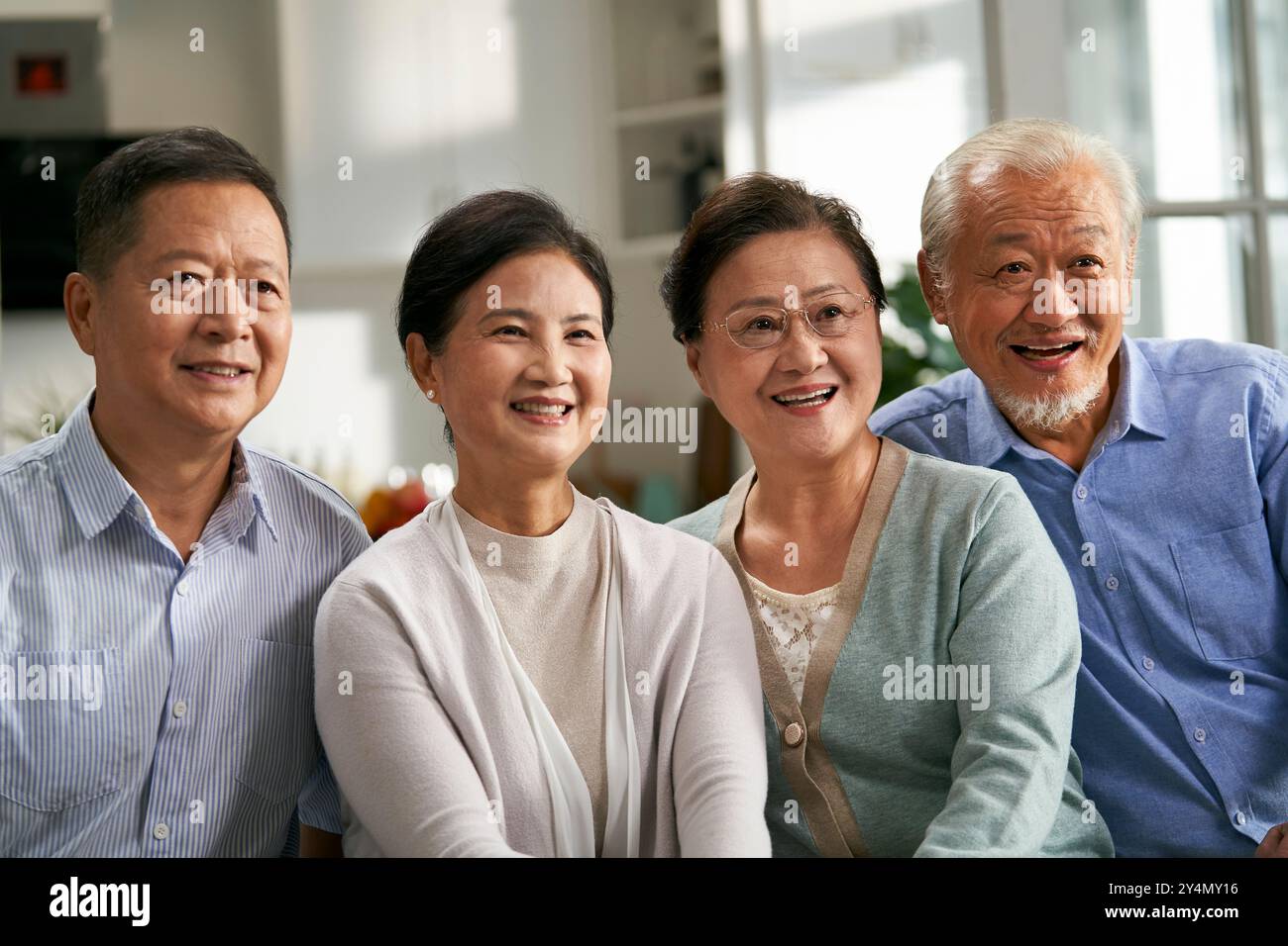 due coppie asiatiche senior felici sedute sul divano a casa a guardare la tv insieme Foto Stock