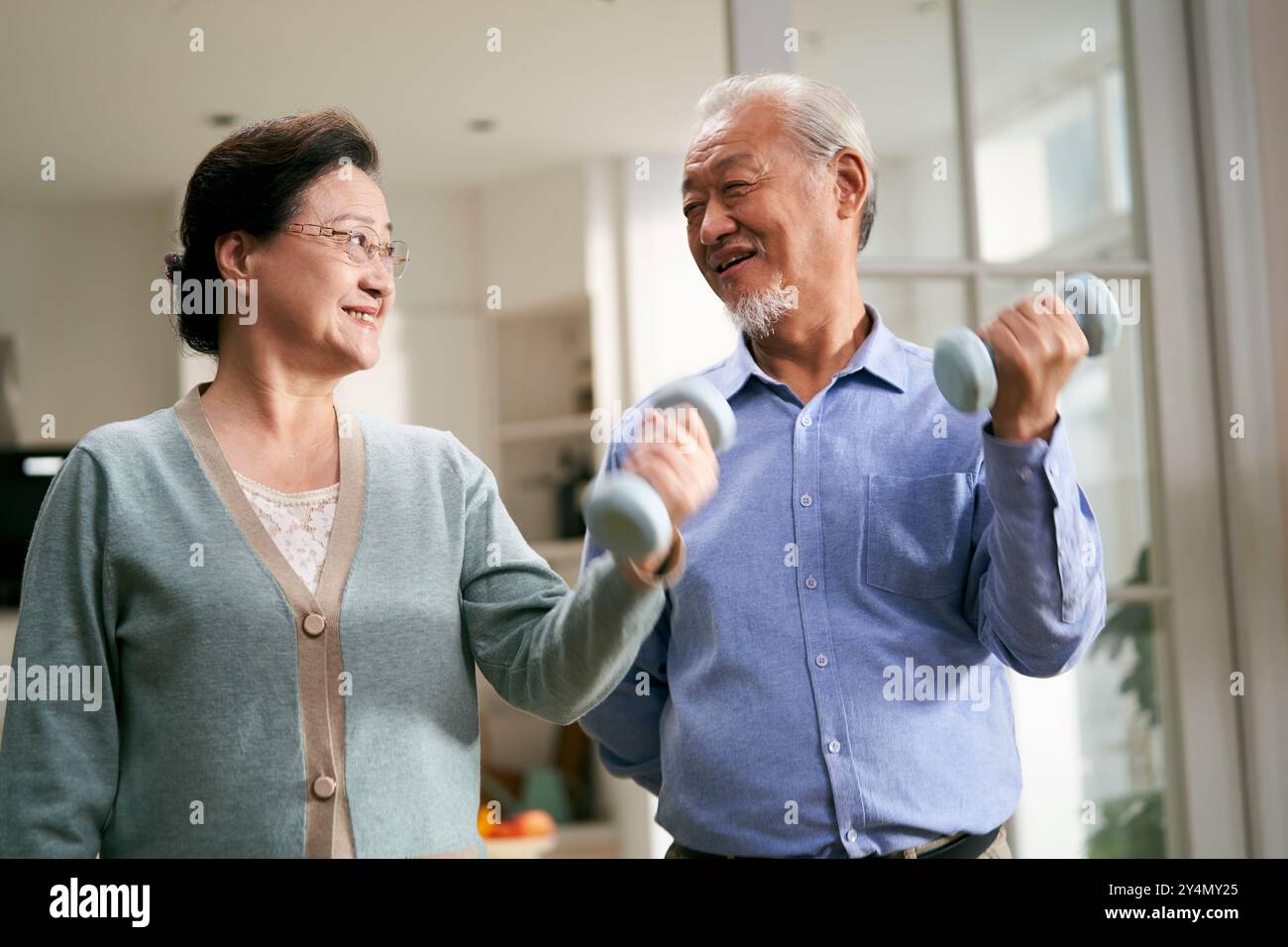 felice senior coppia asiatica esercizio a casa utilizzando manubri Foto Stock