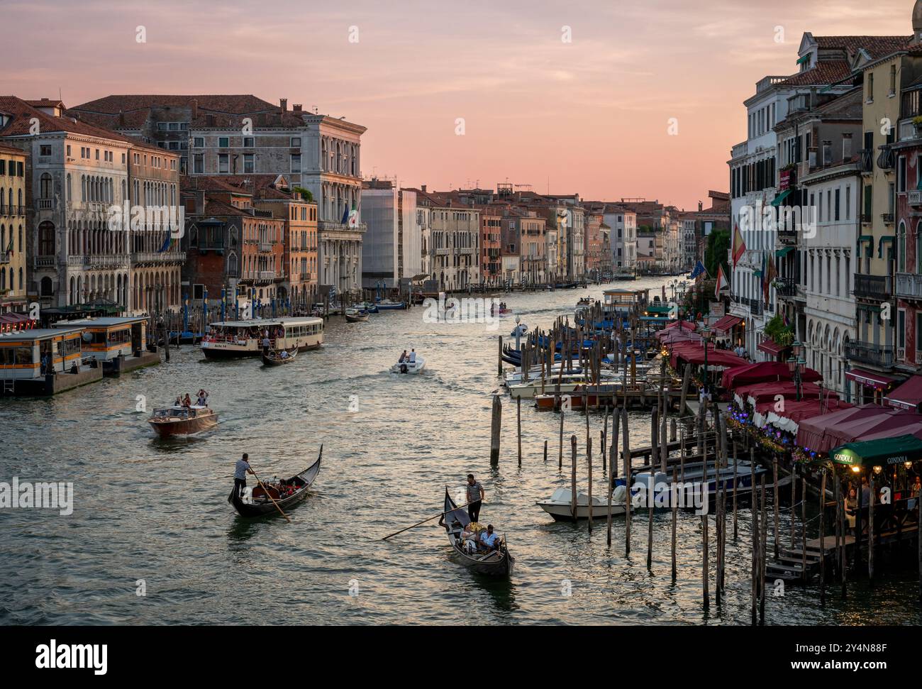 Vista dal Ponte di Rialto dei gondolieri che regnano sull'acqua del Canal grande con i turisti al tramonto a Venezia Italia Europa Foto Stock