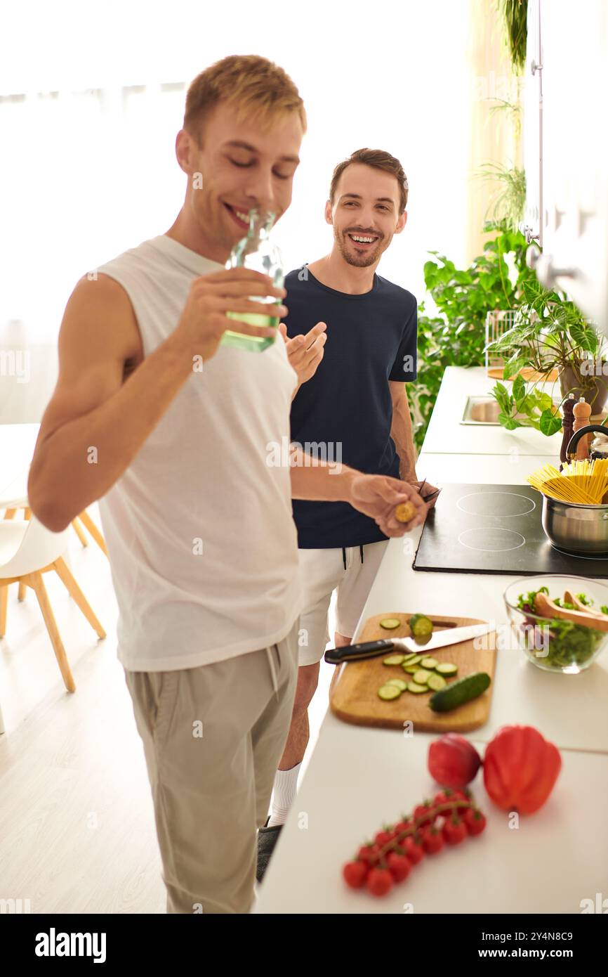 Due uomini tritano volentieri le verdure e preparano un'insalata fresca, godendosi momenti di qualità insieme nella loro elegante cucina. Foto Stock