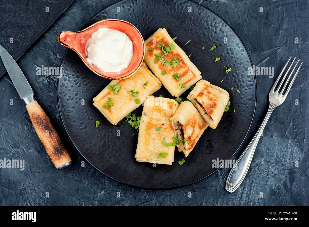 Appetitosi pancake ripieni di carne e panna acida su un piatto. Posizione piatta. Foto Stock