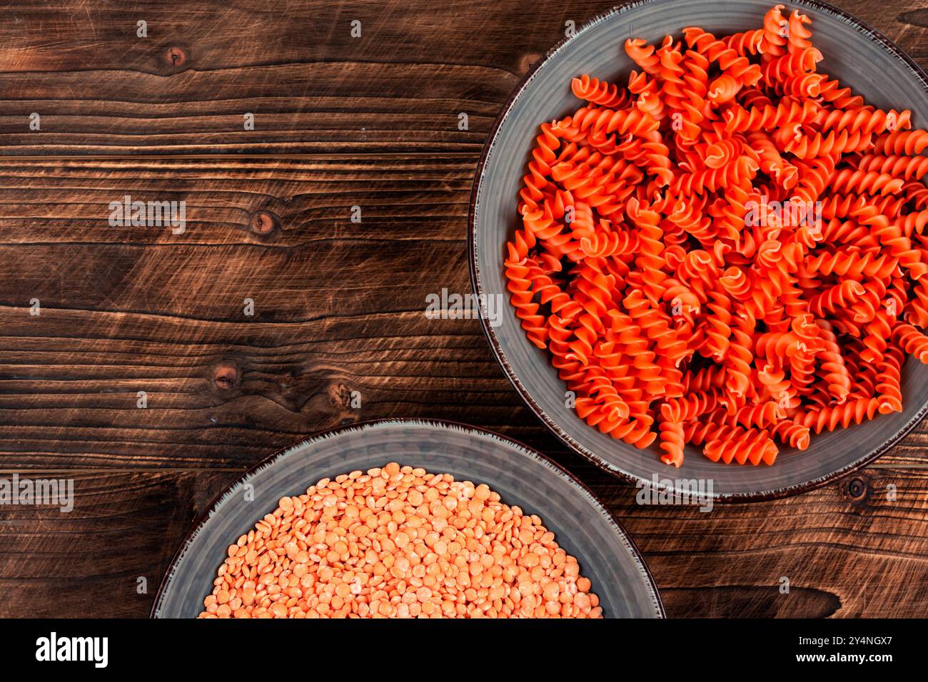 Macaroni crudi e secchi. Pasta vegana cruda o maccheroni, fusilli di lenticchie rosse sul piatto. Copia spazio. Foto Stock
