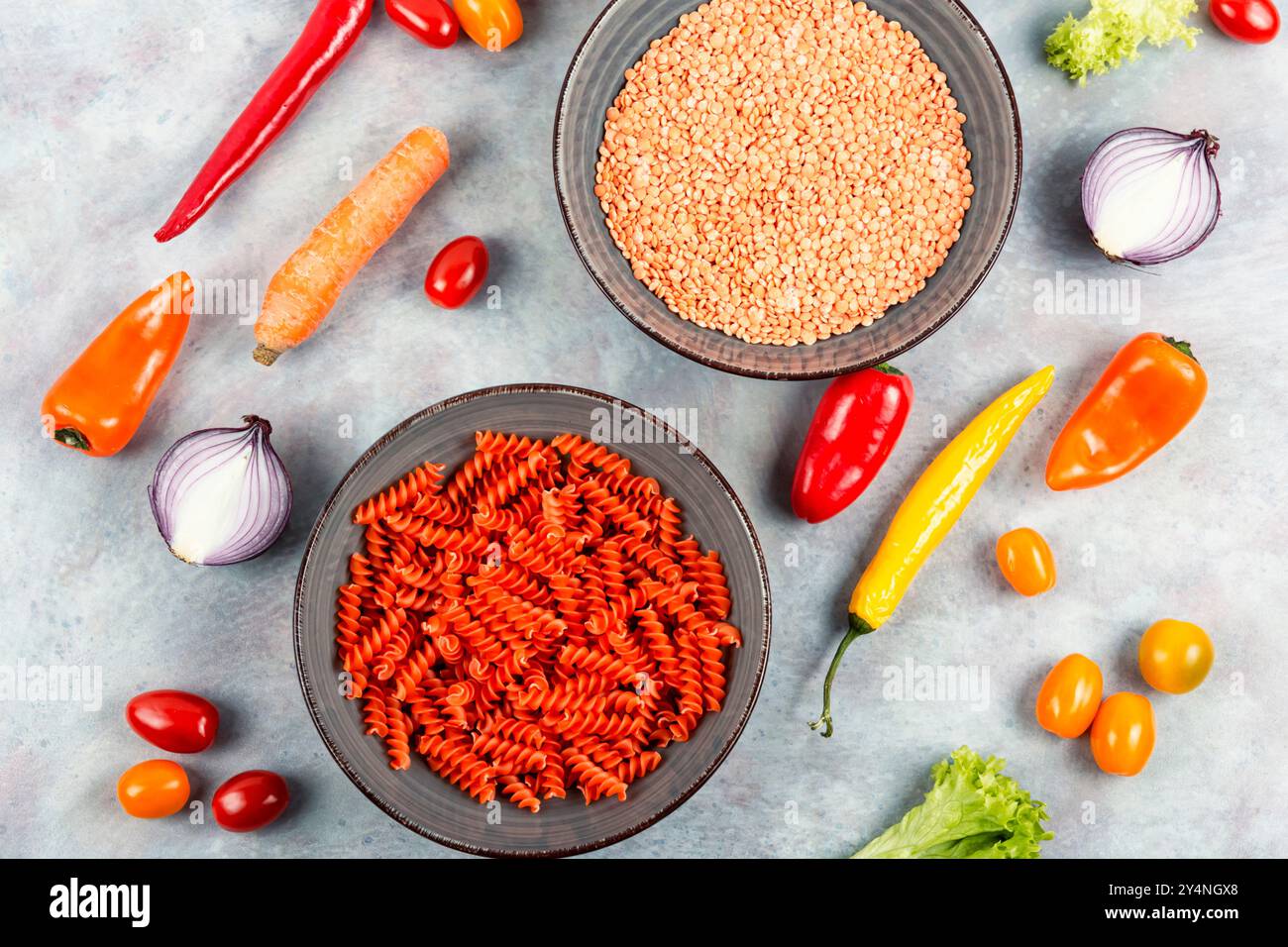 Macaroni crudi e secchi. Pasta vegana cruda, fusilli di lenticchie rosse sul piatto. Vista dall'alto Foto Stock