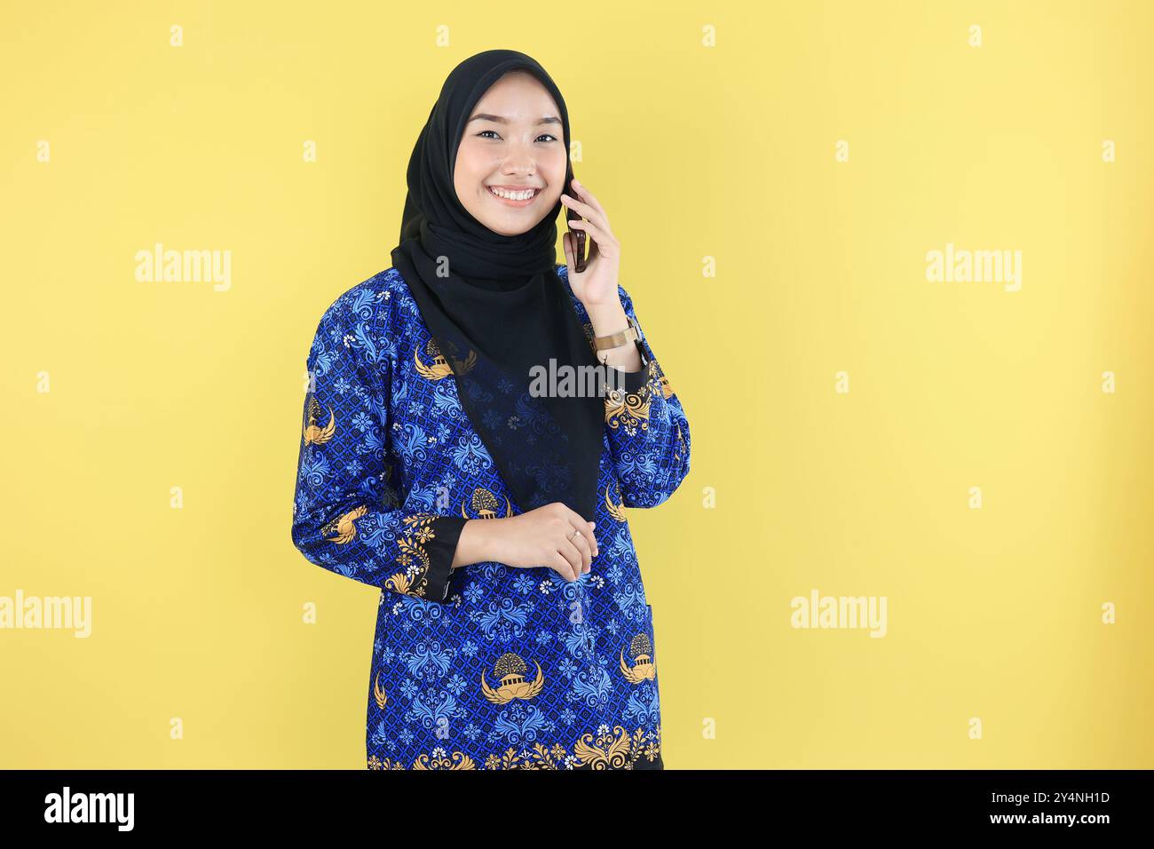 Donna allegra lavoratrice del governo indonesiano che indossa Baju Korpri, fa una chiamata o un telefono, guarda la fotocamera. Foto Stock