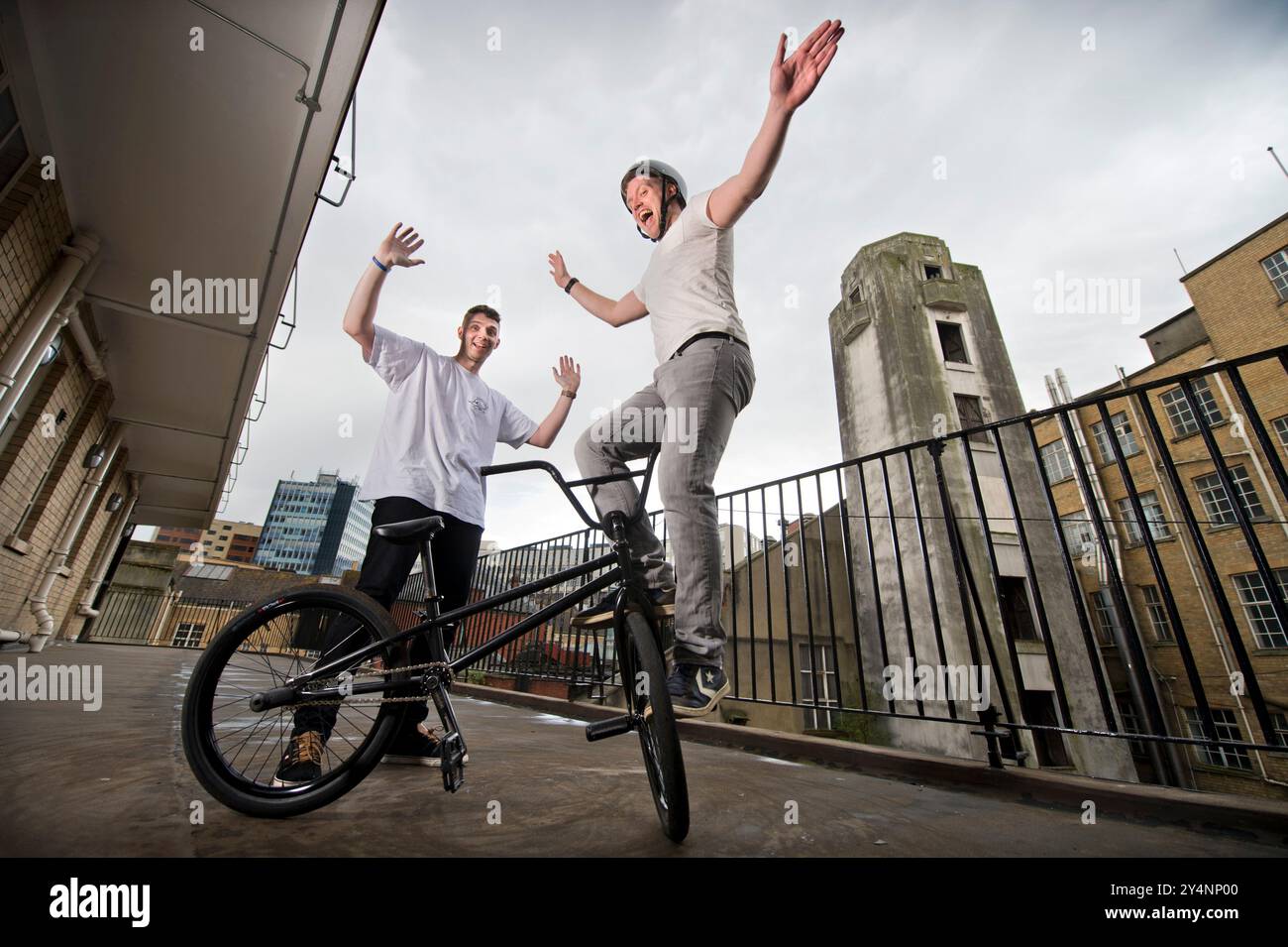 L'istruttore BMX Matti Hemmings (a sinistra) insegna una acrobazia BMX "D Truck" su un balcone dell'edificio della vecchia stazione dei vigili del fuoco di Bristol. Foto Stock