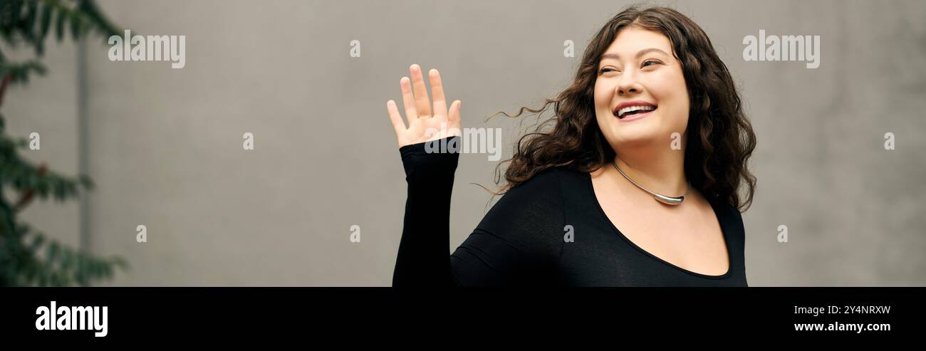 Una giovane donna di grandi dimensioni irradia gioia mentre esplora l'aria aperta in una splendida giornata autunnale vestita in modo impeccabile. Foto Stock