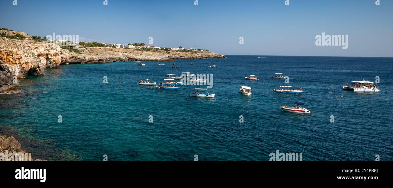 Un panorama di barche turistiche raccolte fuori dagli ingressi delle grotte vicino a Santa Maria di Leuca nella provincia di Lecce, Puglia, Italia Foto Stock