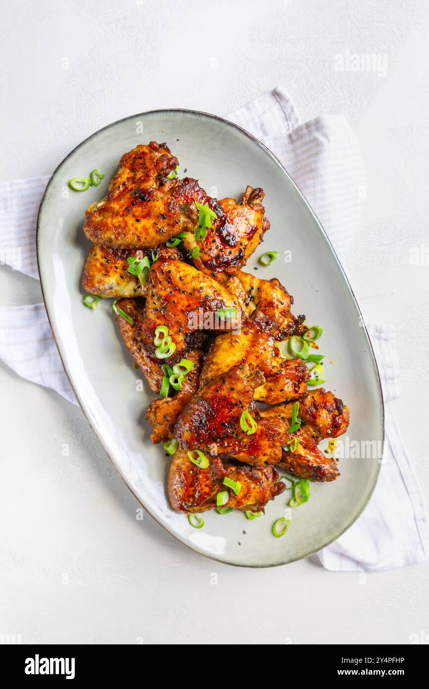 Ali di pollo fatte in casa in stile asiatico con cipolle verdi sul piatto da portata Foto Stock