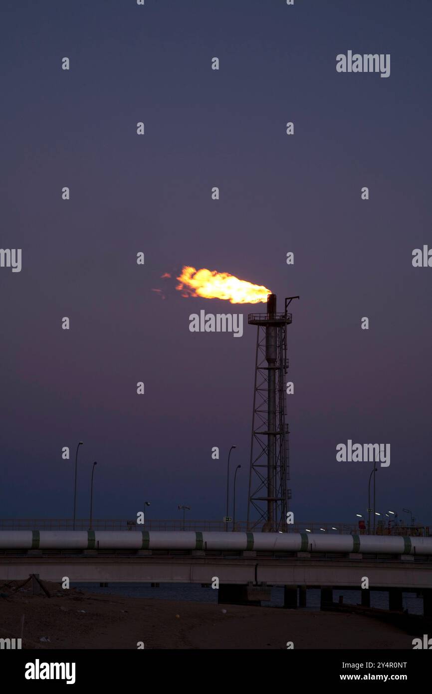 La luce gassosa brucia brillantemente presso l'impianto di rigassificazione lungo la costa, illuminando il cielo serale di Huelva, nel sud-ovest della Spagna. Foto Stock