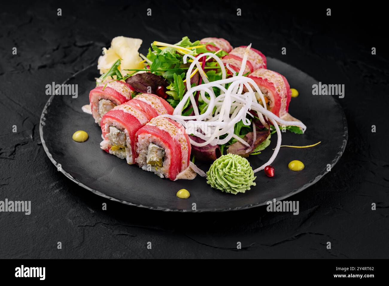 Presentazione artistica di sushi roll con decorazioni fresche su sfondo scuro Foto Stock