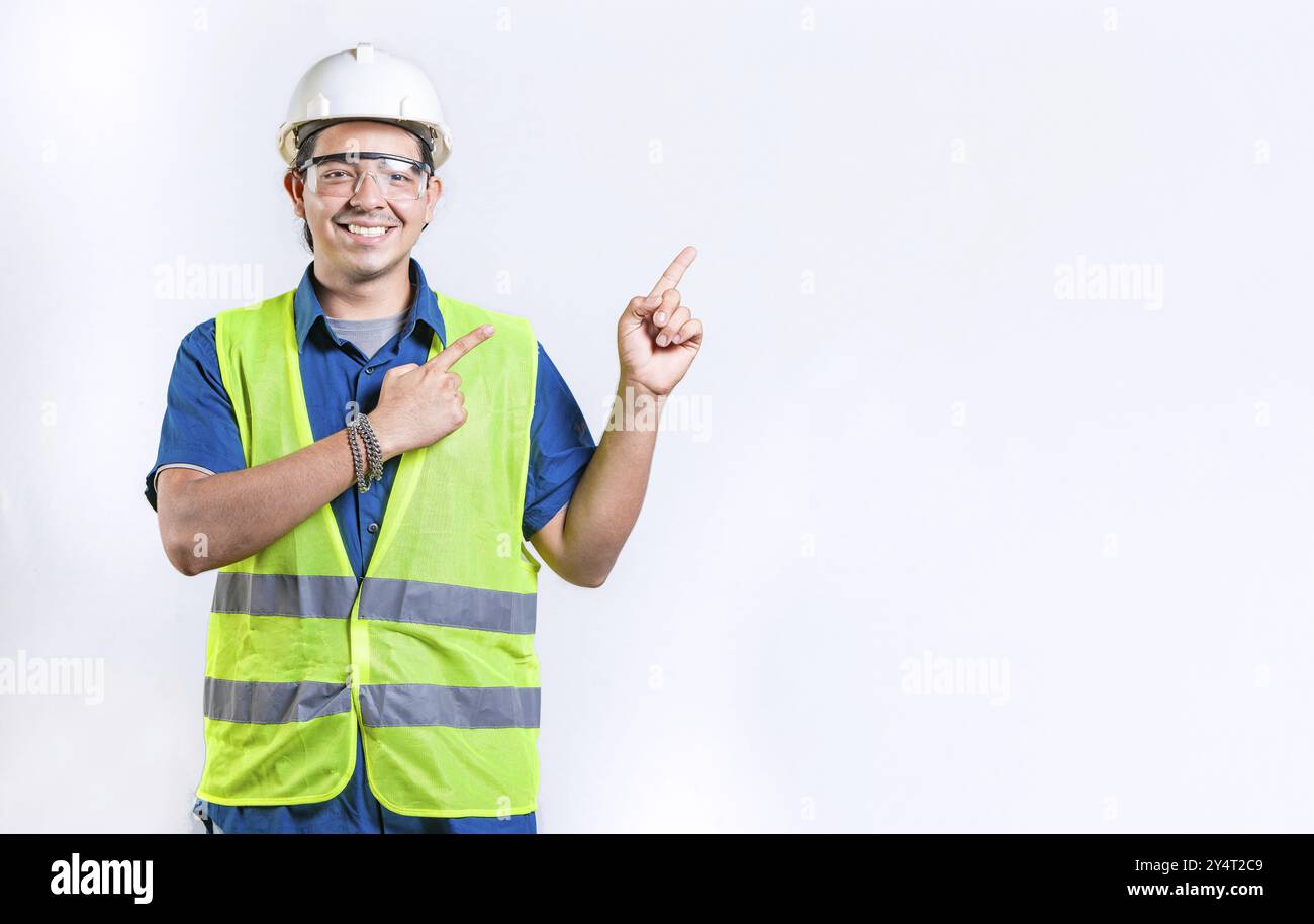 Un ingegnere maschio felice che indica la parte isolata. Ingegnere maschio sorridente che indica uno spazio vuoto isolato Foto Stock