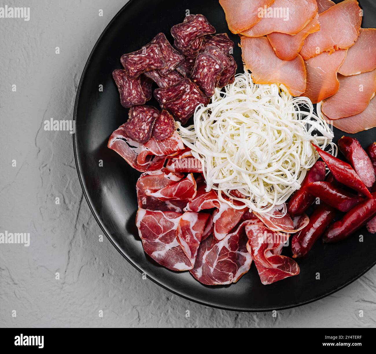 Vista dall'alto di una selezione di salumi con carni e formaggi su un piatto nero Foto Stock