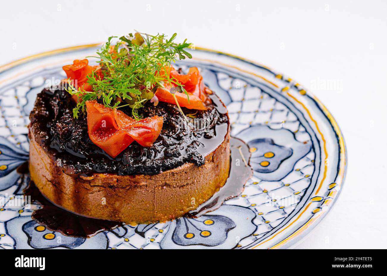 Squisito tatuino con tarte capovolto decorato con fragole ed erbe su un piatto a motivi geometrici Foto Stock