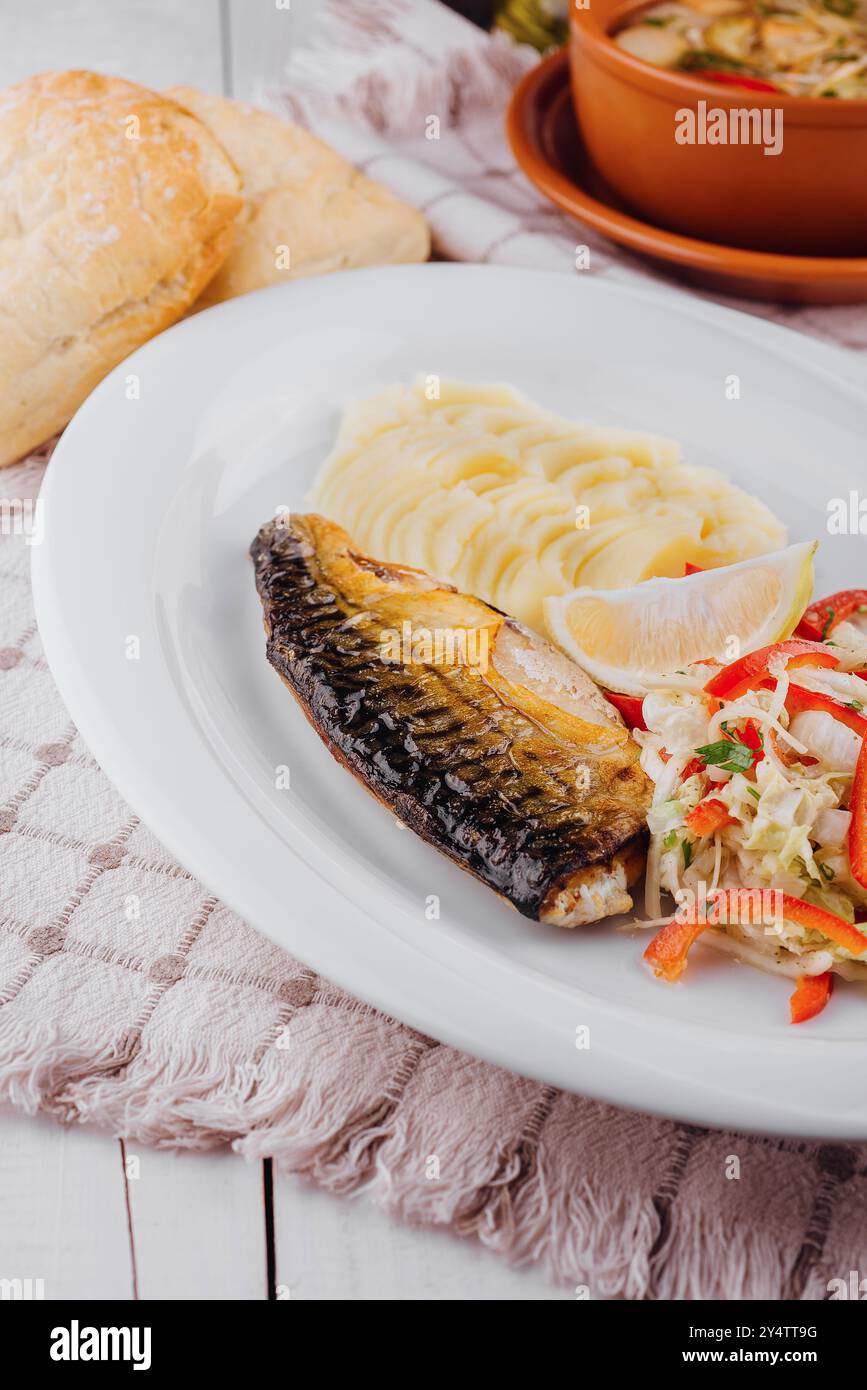 Sgombro alla griglia servito con purè di patate e insalata su piatto bianco con limone, cibo sano Foto Stock