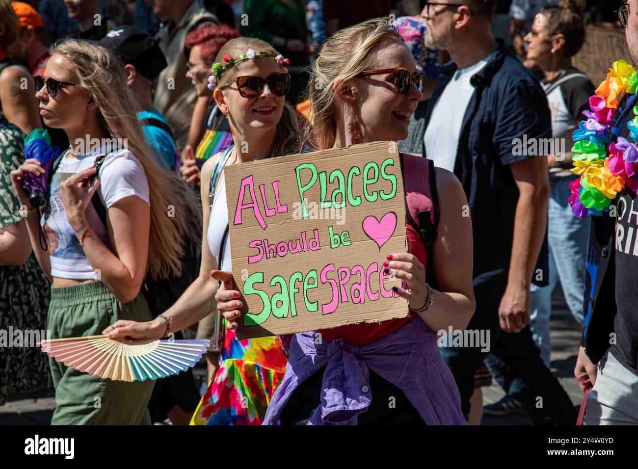 Tutti i posti devono essere spazi sicuri. Donna con un cartello di cartone alla parata Helsinki Pride 2024 a Helsinki, Finlandia. Foto Stock Tutti i posti devono essere spazi sicuri. Donna con un cartello di cartone alla parata Helsinki Pride 2024 a Helsinki, Finlandia. Foto Stock