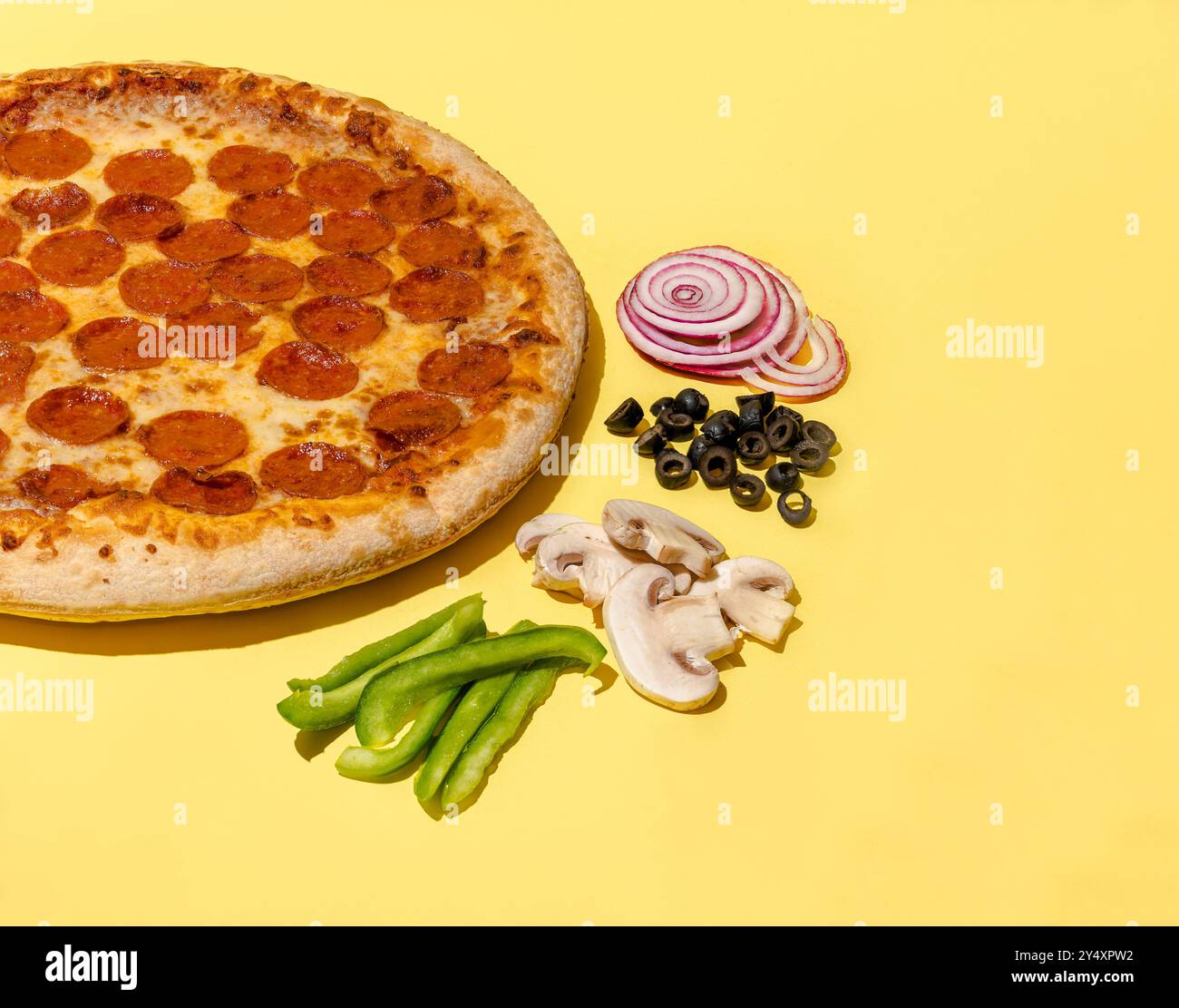 Pizza al peperoni condimenti eccellenti cipolla olive funghi peperoni su sfondo giallo foto studio con spazio fotocopie Foto Stock