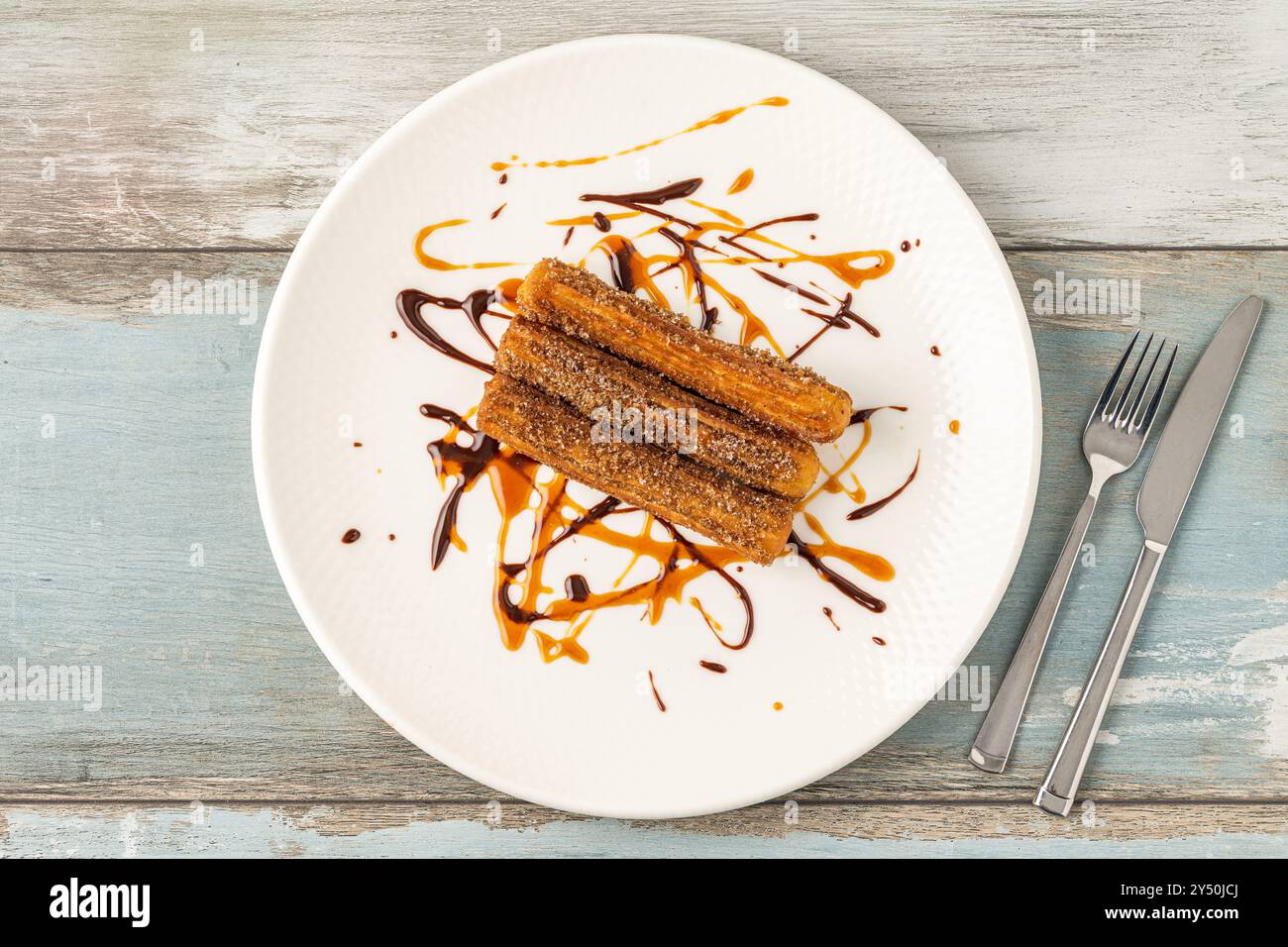 Churros caldi con salsa di cioccolato su tavola di legno. Foto Stock