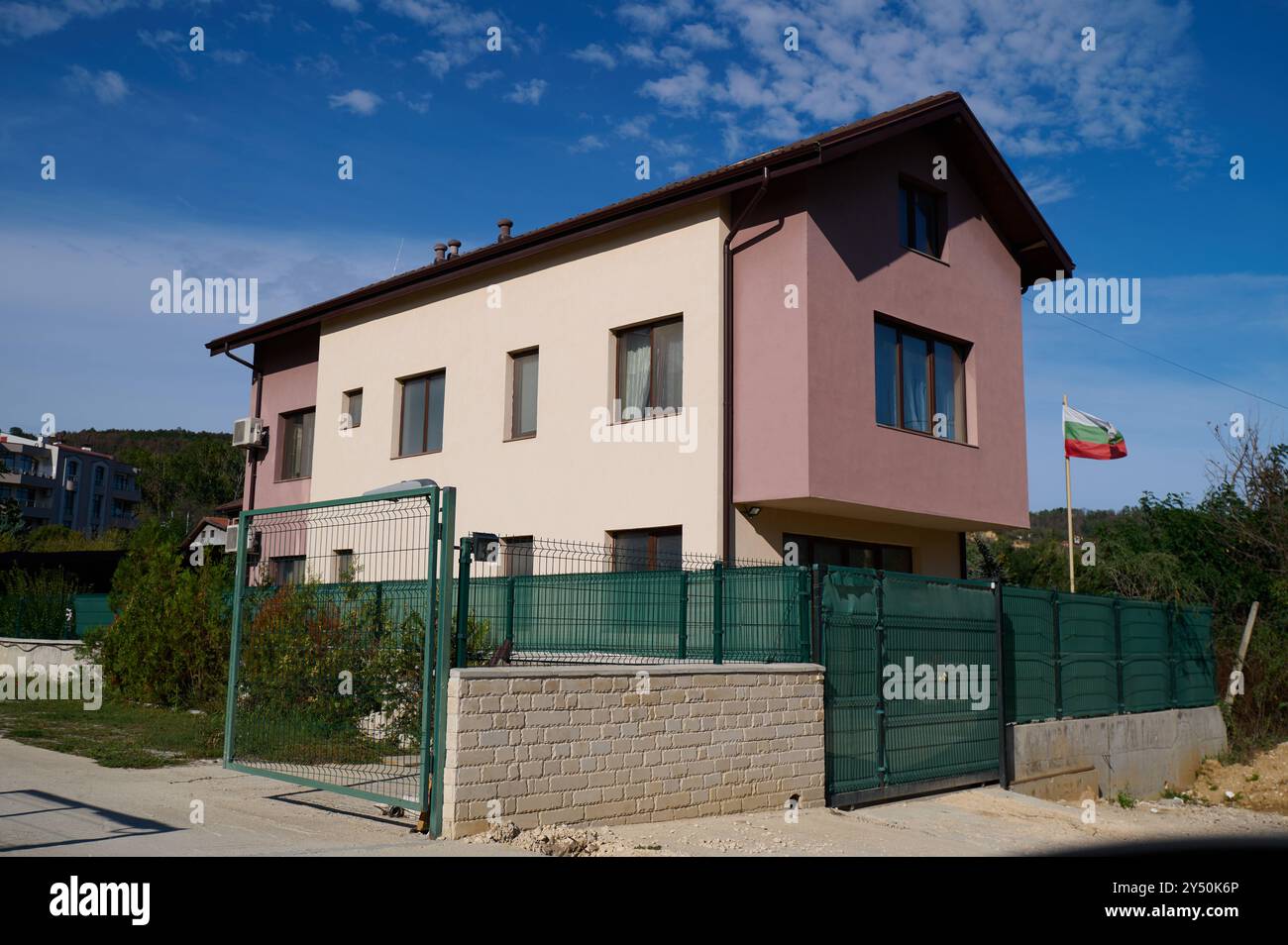 Moderno edificio residenziale a due piani con uno schema colore unico in un quartiere periferico sotto un cielo azzurro Foto Stock