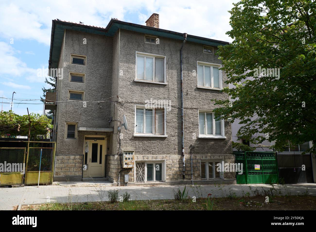 Edificio residenziale che mostra architettura della metà del secolo in un quartiere tranquillo, circondato da alberi e cielo blu Foto Stock