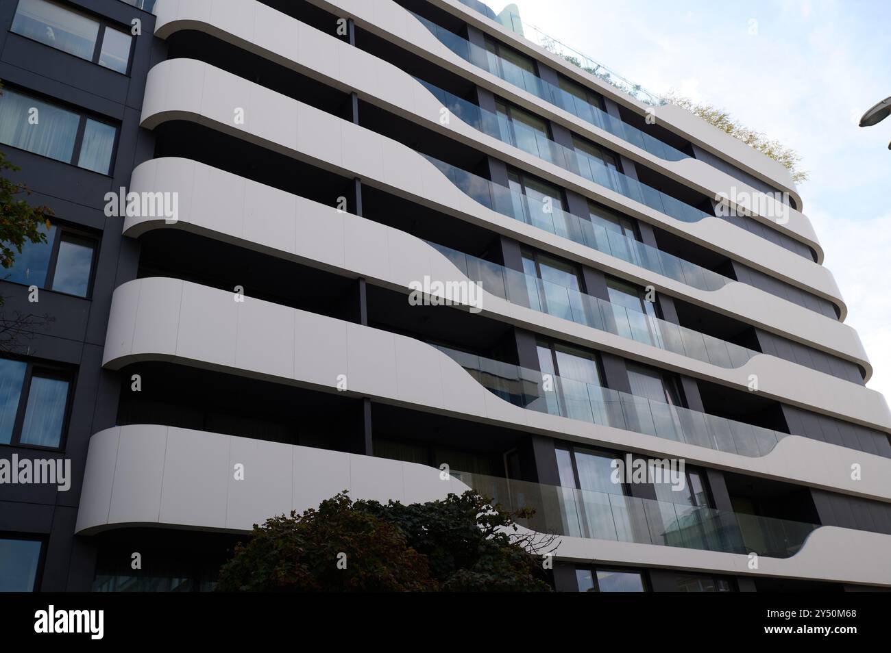 Moderno design architettonico di un elegante edificio residenziale caratterizzato da balconi curvi in un ambiente urbano Foto Stock