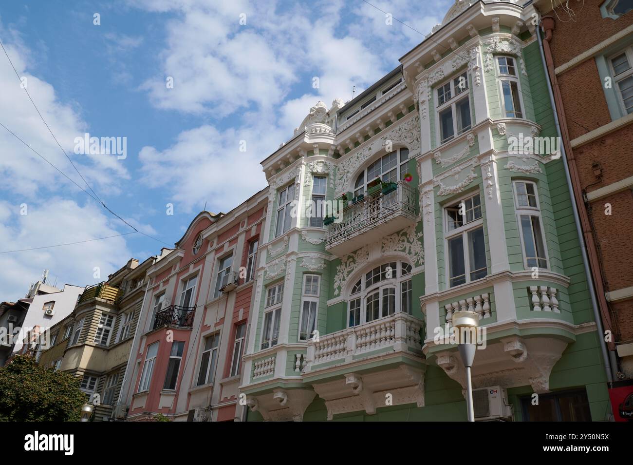 Elegante architettura degli inizi del XX secolo in una vivace strada cittadina che mostra dettagli intricati e colori pastello contro un cielo limpido Foto Stock