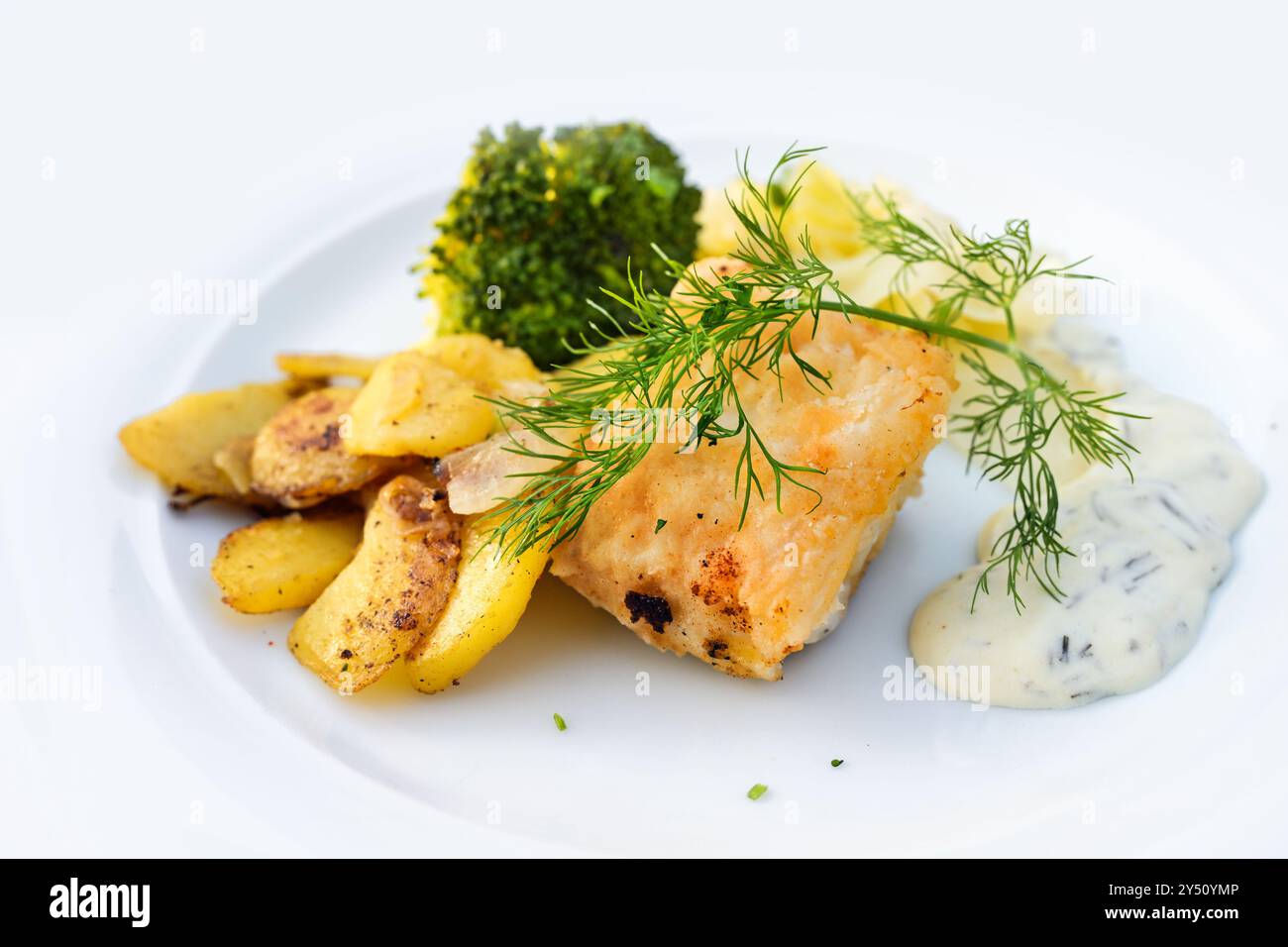 Filetto di pesce fritto con patate arrosto, broccoli, salsa remoulade e contorno di aneto, servito su un piatto bianco, piatto salutare in un menu della cena, copia di spac Foto Stock