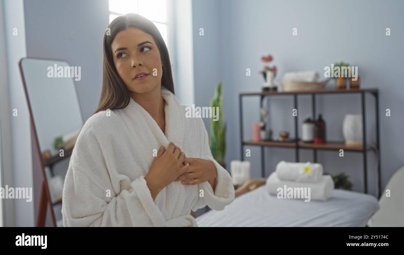 Una giovane donna in abito bianco alla spa si gode un momento di relax in un centro benessere circondato da un arredamento minimalista Foto Stock